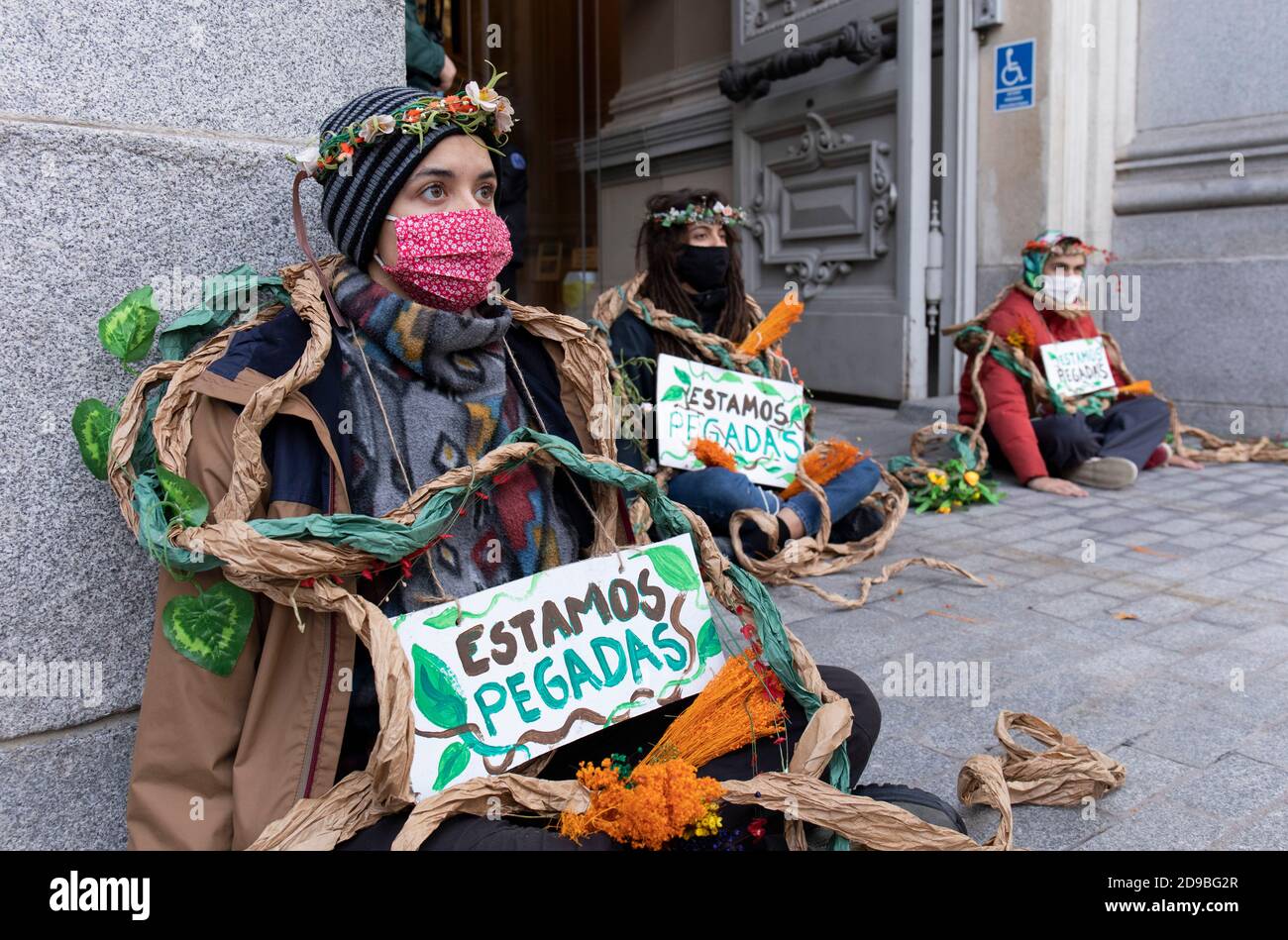 Gli attivisti che indossano il facemask sono visti incollati al marciapiede del Ministero dell'Agricoltura mentre portano i cartelli che riportano "siamo incollati" durante la dimostrazione.durante la terza ribellione internazionale, il movimento della ribellione estinzione ha bloccato l'ingresso del Ministero dell'Agricoltura questa mattina per rivendicare la protezione della biodiversità a Madrid. Foto Stock