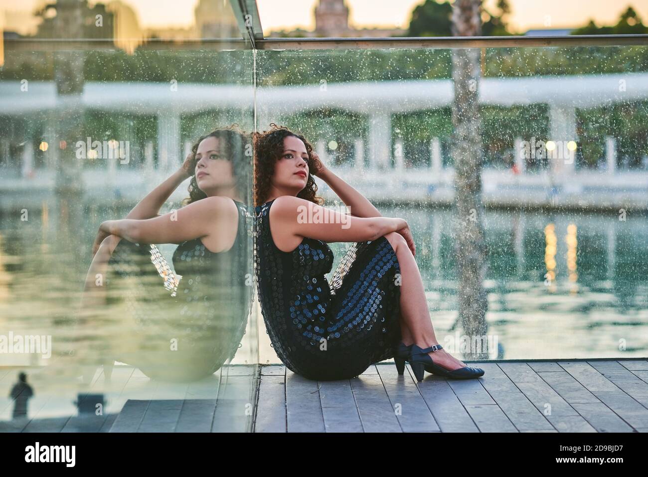 Donna seduta al tramonto sul lungomare. Foto Stock