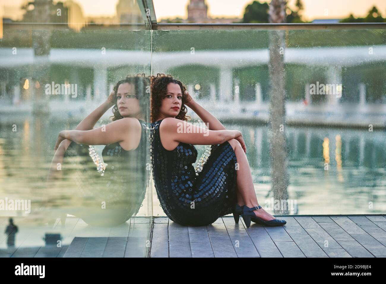 Donna seduta al tramonto sul lungomare. Foto Stock