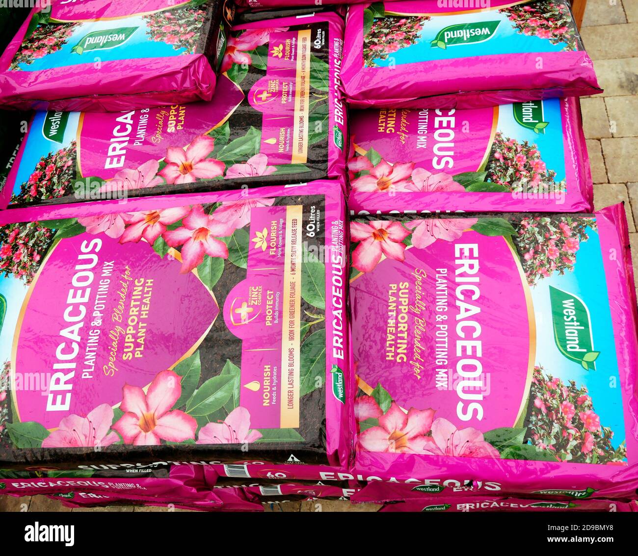 Una pila di sacchetti rosa di composto ericaceo con John Innes in un centro giardino Foto Stock
