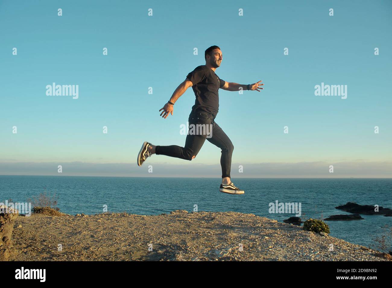 Uomo che salta su una scogliera Foto Stock