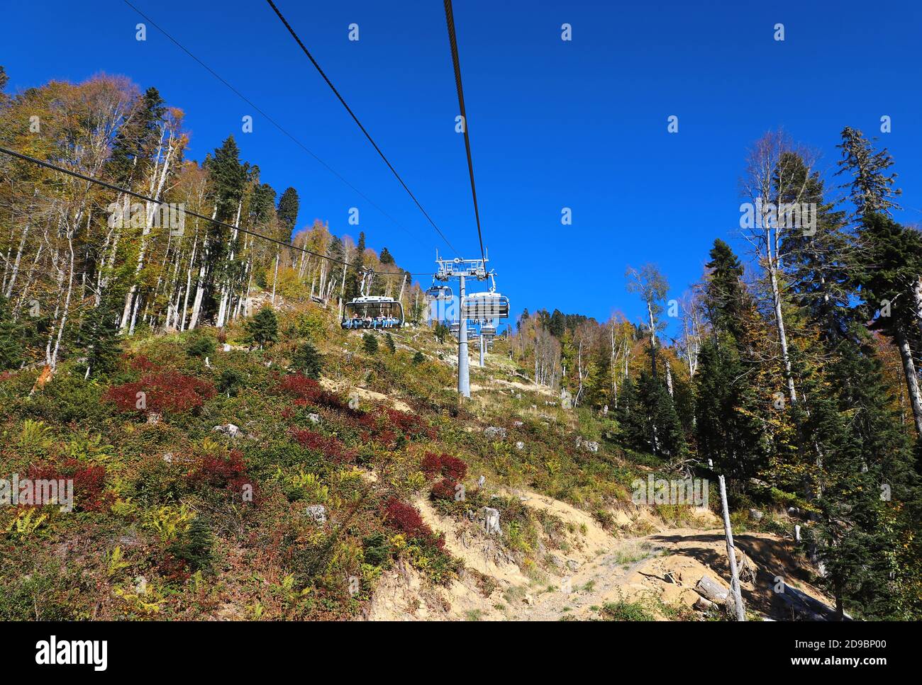 Funivia o skilift con splendida vista sulla foresta d'autunno e cielo blu sullo sfondo. Gita in montagna. Foto Stock