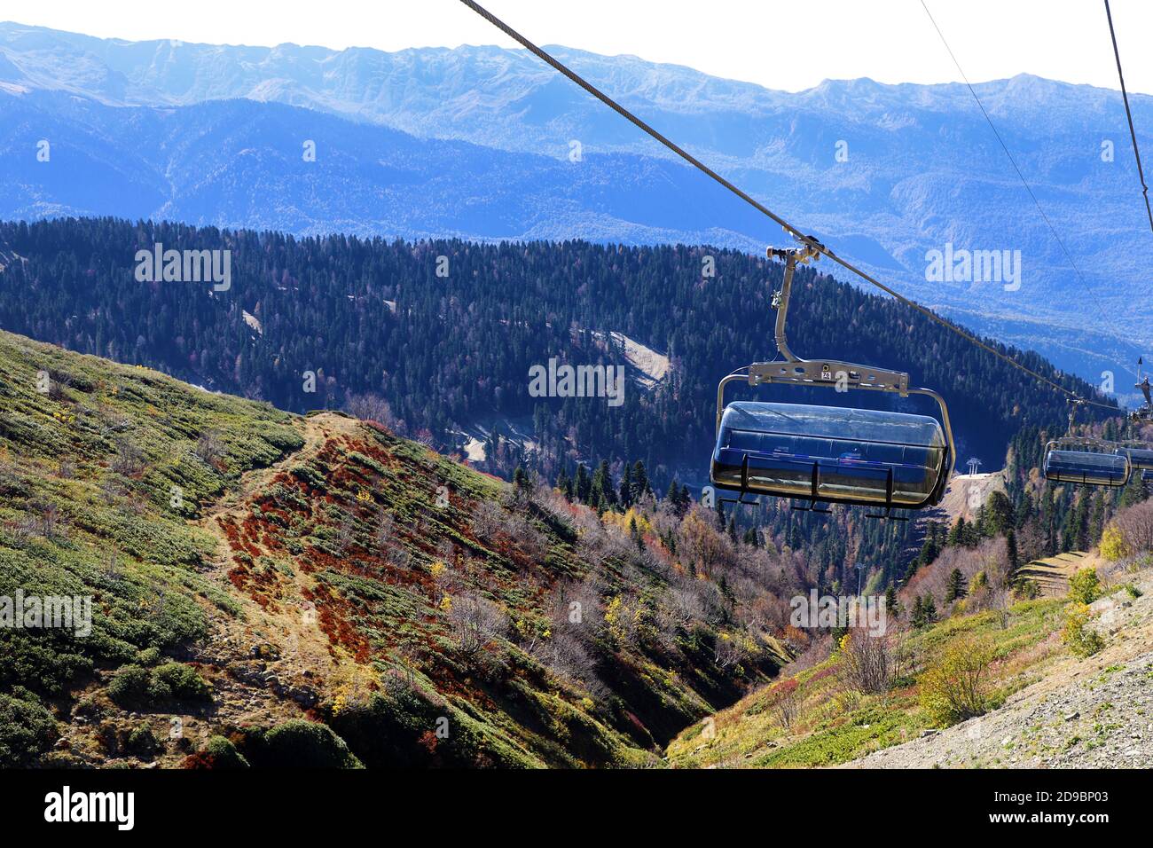 Funivia o skilift aperti in montagna. Vista sulla foresta d'autunno e cielo blu sullo sfondo. Foto Stock