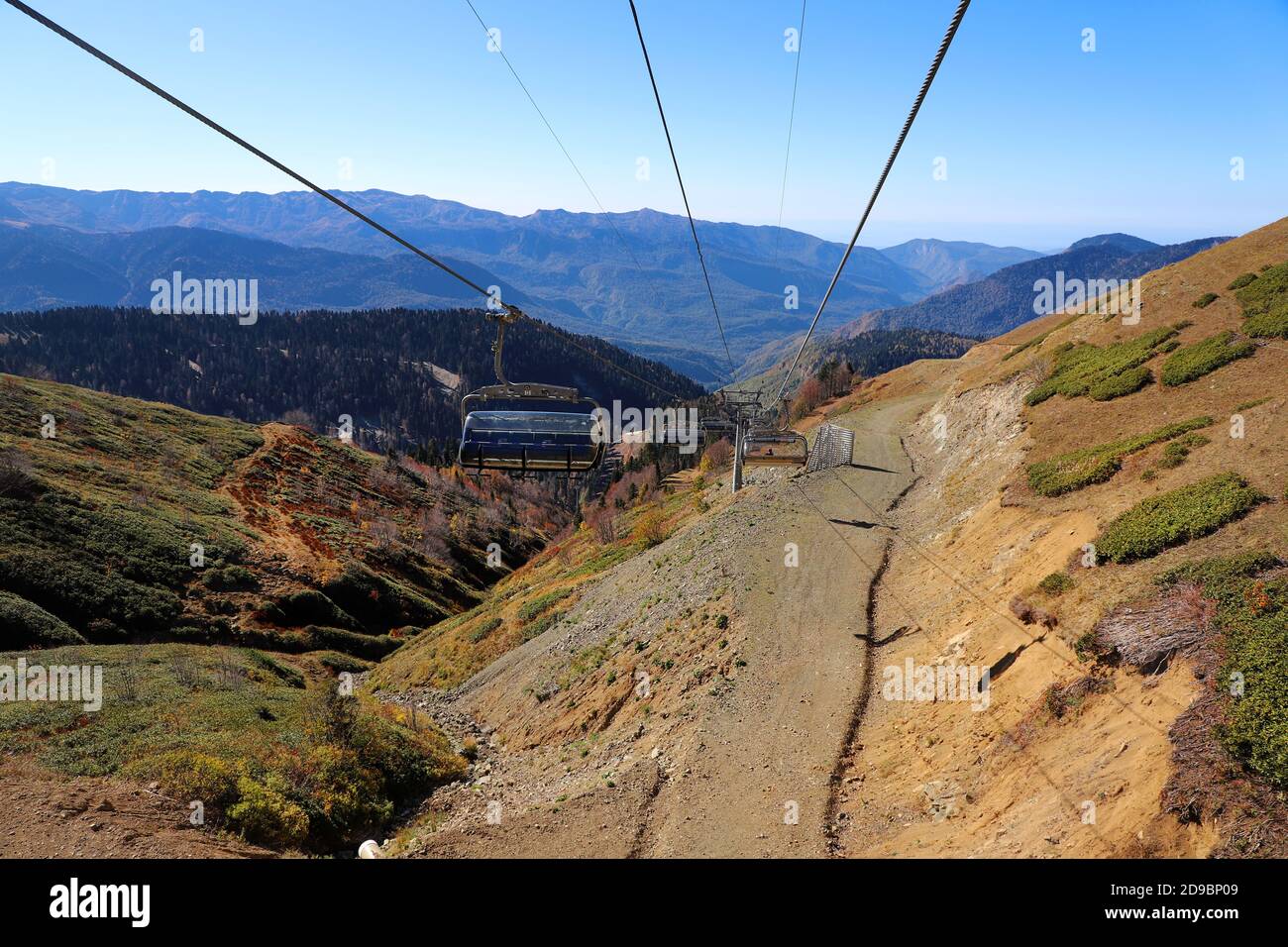 Funivia o skilift con vista mozzafiato sulla foresta d'autunno e sulle alte montagne. Foto Stock