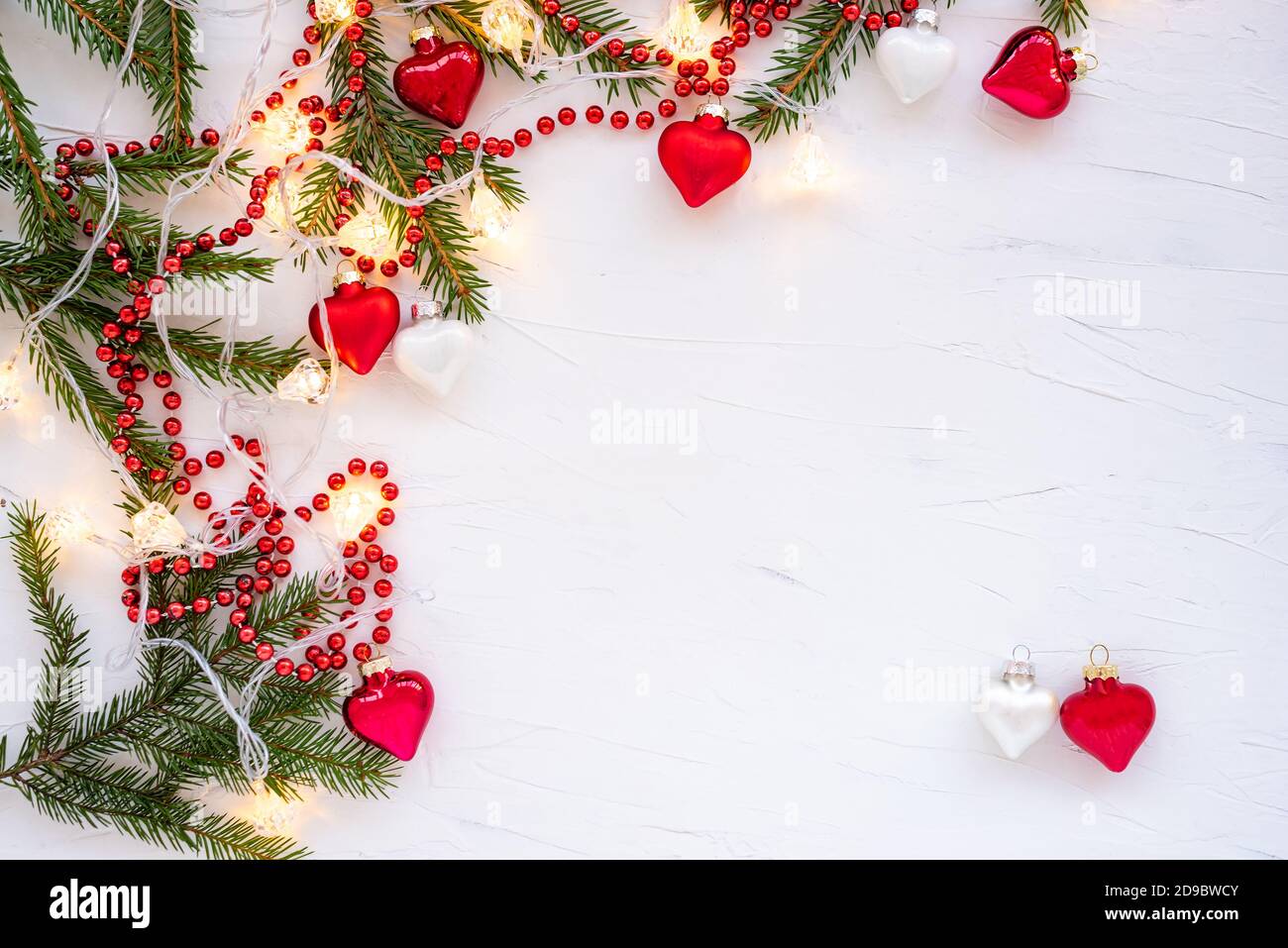 Cornice fatta di rami di un albero di Natale e decorazioni in vetro a forma di cuori. Foto Stock