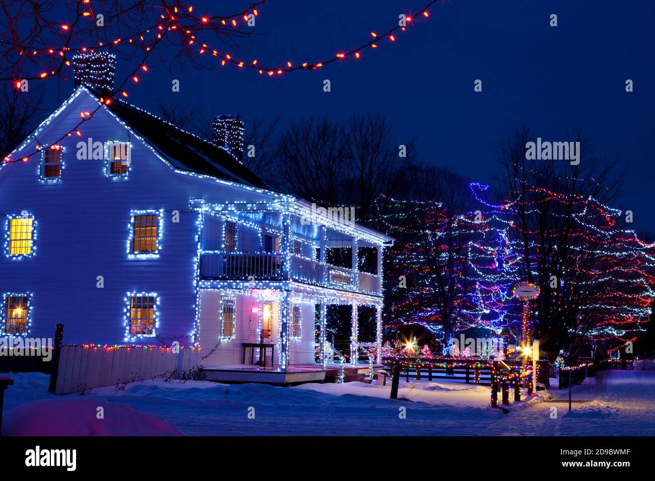 Edifici storici, alberi e recinzioni decorati con luci di Natale a Upper Canada Village, Morrisburg, Ontario, Canada Foto Stock
