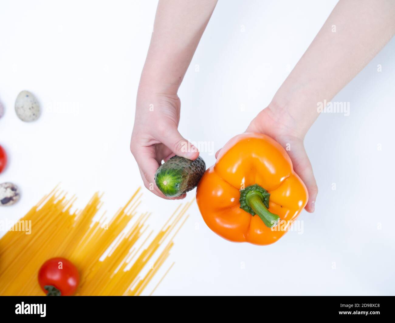 le mani dei bambini tengono le verdure fresche in mano. concetto di nutrizione sana per i bambini. verdure fresche su sfondo bianco Foto Stock