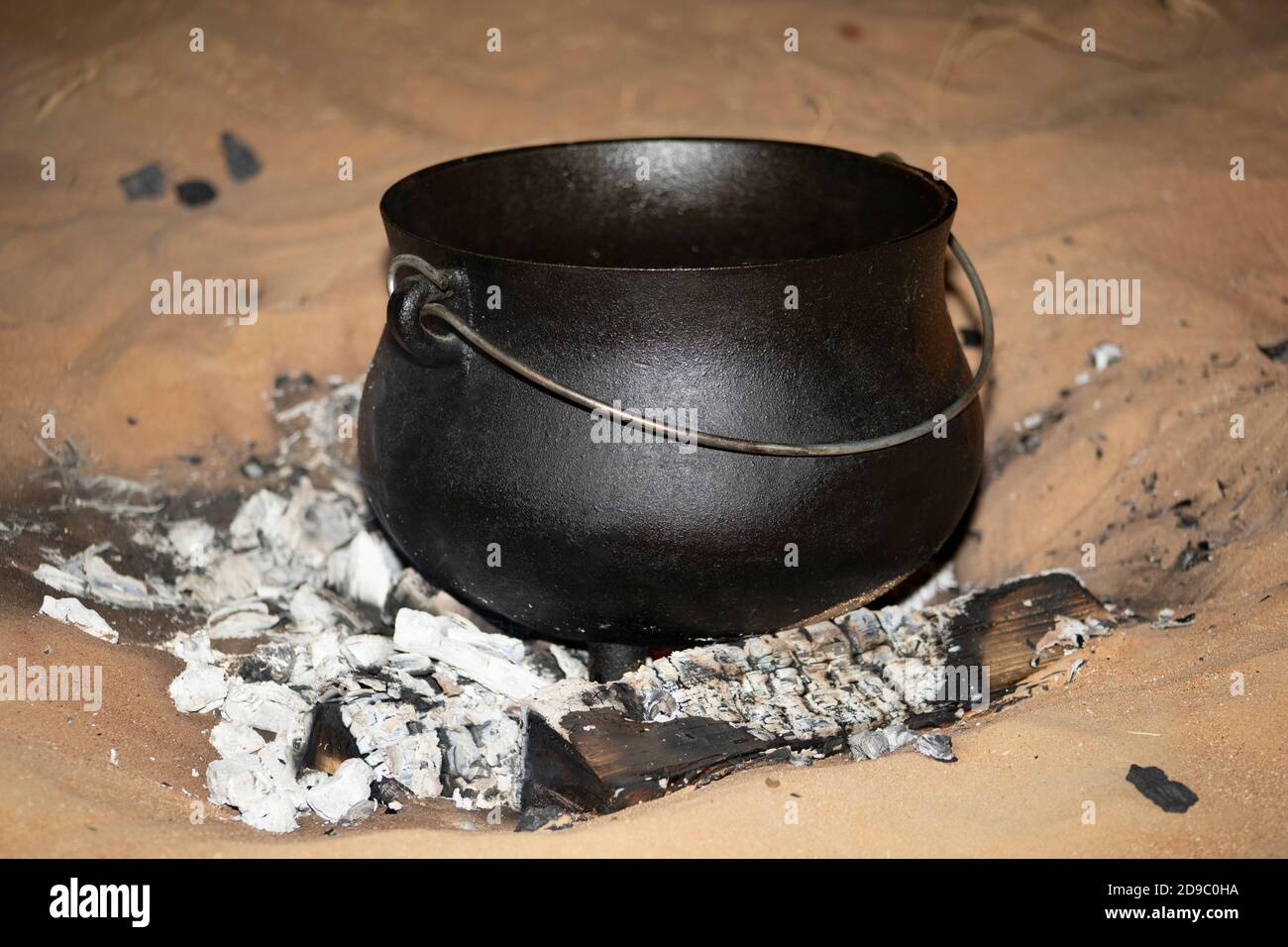 Un ferro di getto 'dutch-forno' in piedi in un campo di fuoco in la sabbia del deserto Foto Stock