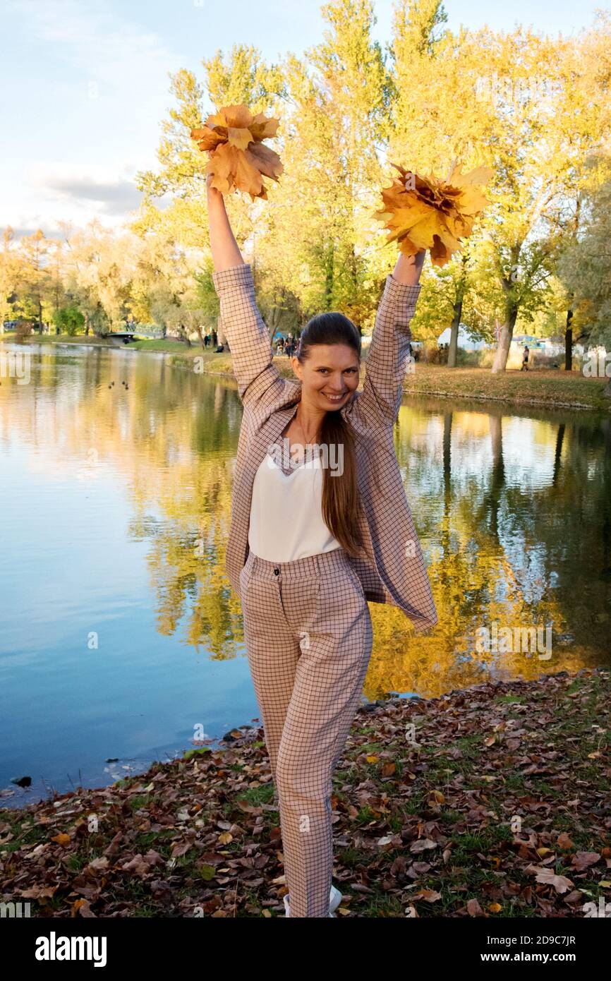 Giovane donna in autunno Parco divertirsi con le foglie. Il concetto di un buon umore in una passeggiata Foto Stock