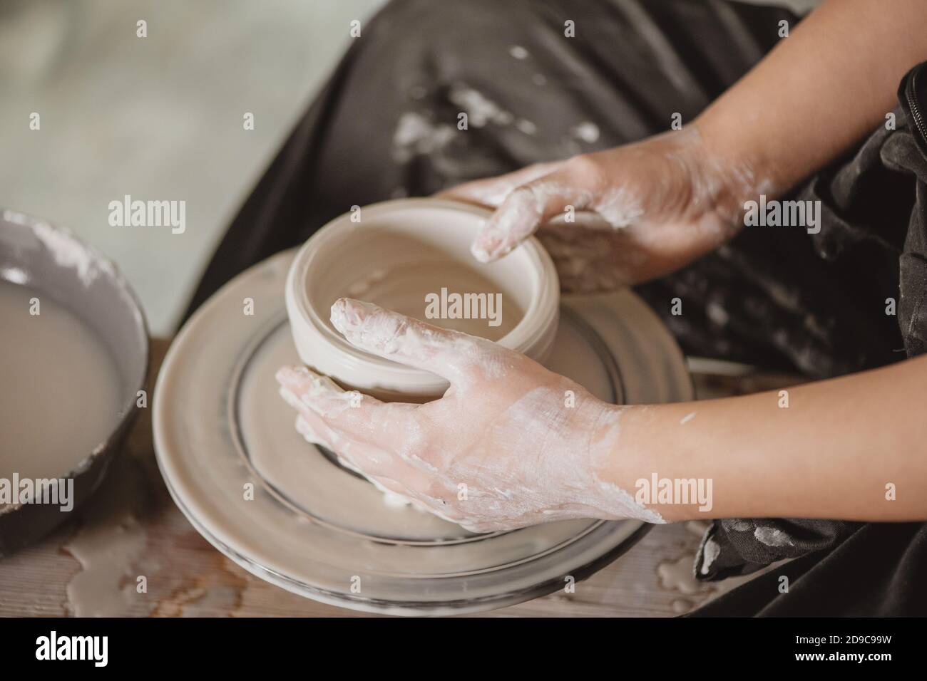 Primo piano di mani di donna che creano vaso di terra sul cerchio di vasaio. Foto Stock