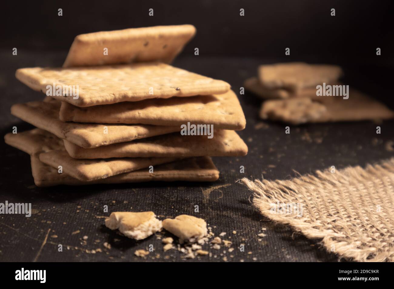 Cracker asciutti con lino e semi di sesamo su sfondo scuro. Pubblicità, poster. Foto Stock
