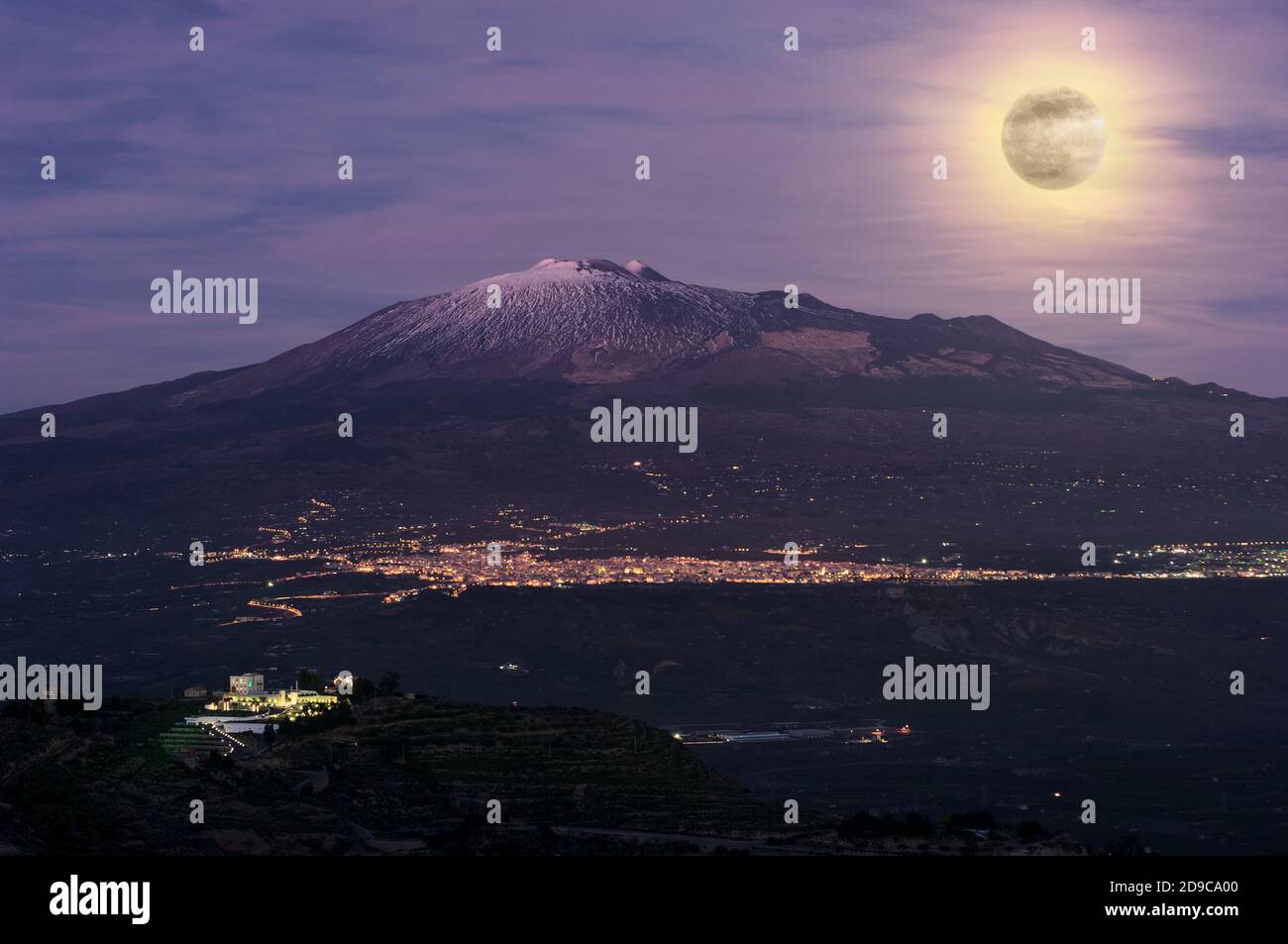 Paesaggio notturno con luna piena sulla città e vulcano Etna In Sicilia punto di riferimento naturale Foto Stock
