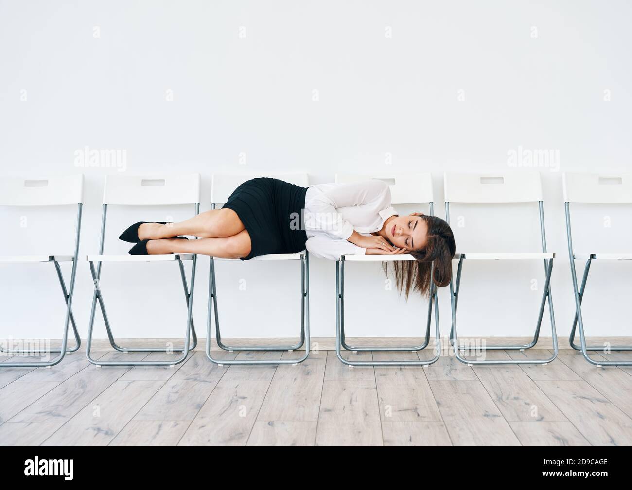 Una donna d'affari stanca e overworked che dormiva sulla sedia alla sala conferenze in ufficio Foto Stock
