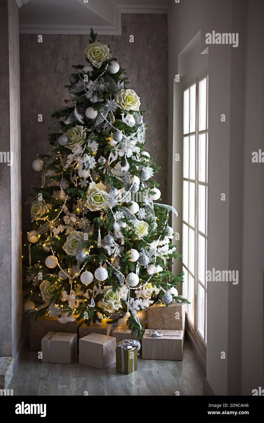 Confezione regalo in confezione oro e arco d'argento sotto l'albero di  Natale con decorazioni bianche. Capodanno, vigilia di Natale, saluti per la  famiglia, comfort e wa Foto stock - Alamy