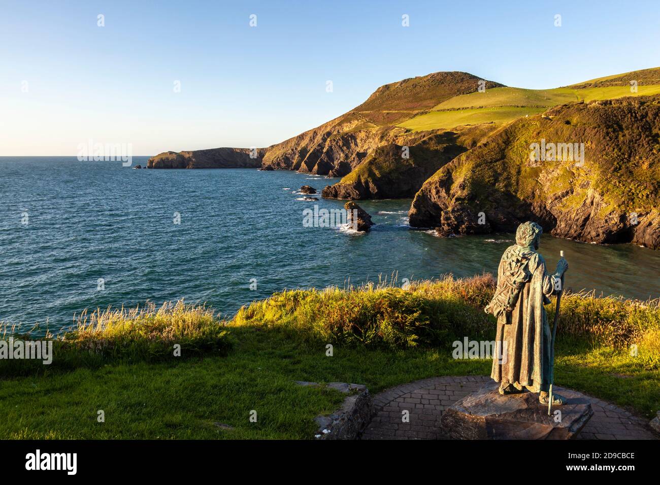 Una vista di Ynys Lochtyn dalla cima della scogliera sopra LLangrannog con la statua di San Crannog in primo piano, Ceredigion, Galles Foto Stock