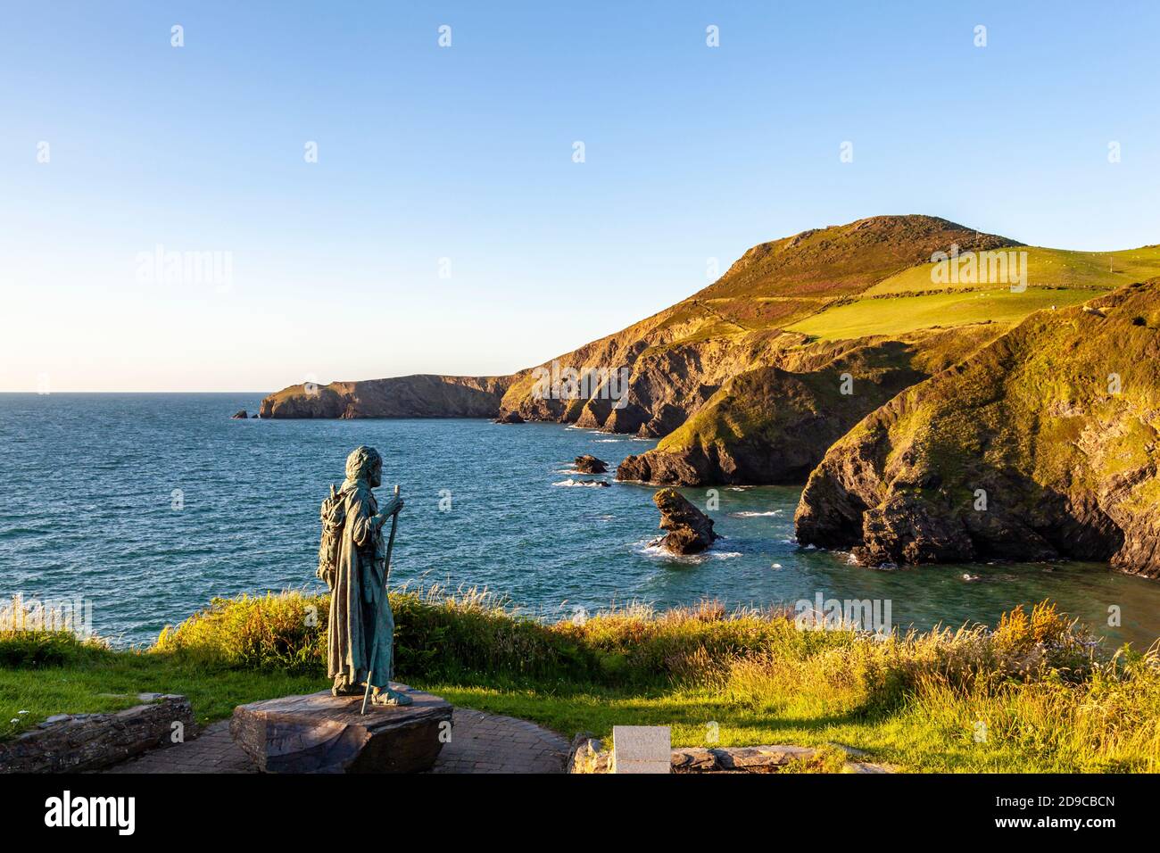 Una vista di Ynys Lochtyn dalla cima della scogliera sopra LLangrannog con la statua di San Crannog in primo piano, Ceredigion, Galles Foto Stock