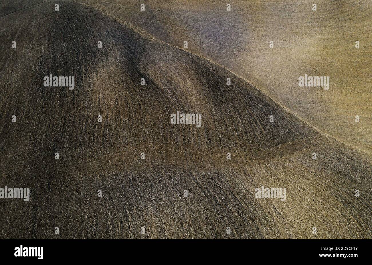 Vista aerea dall'alto sul campo coltivato arato ondulato toscano con pittoreschi punti di luce solare serale con texture che giocano gradualmente con l'ombra della luce. Beau Foto Stock