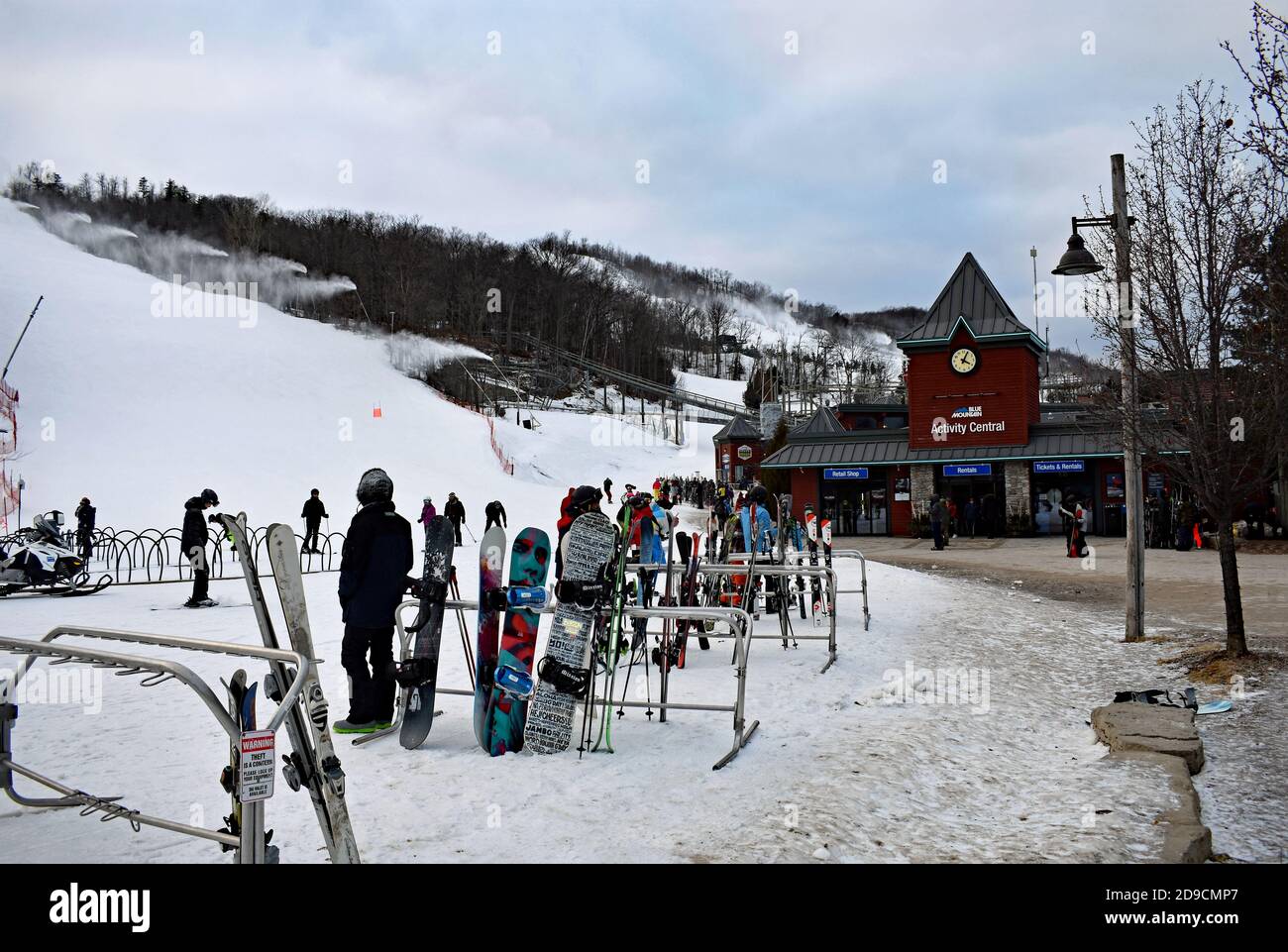 Il centro attività presso il Blue Mountain Resort, Canada. Le tavole da neve vengono riposte contro ringhiere metalliche. Si possono vedere piste da sci con macchine da neve. Foto Stock