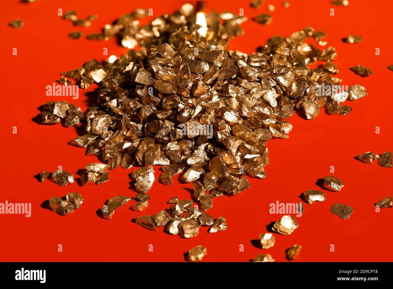 Piccole pietre d'oro brillano su sfondo rosso Foto Stock