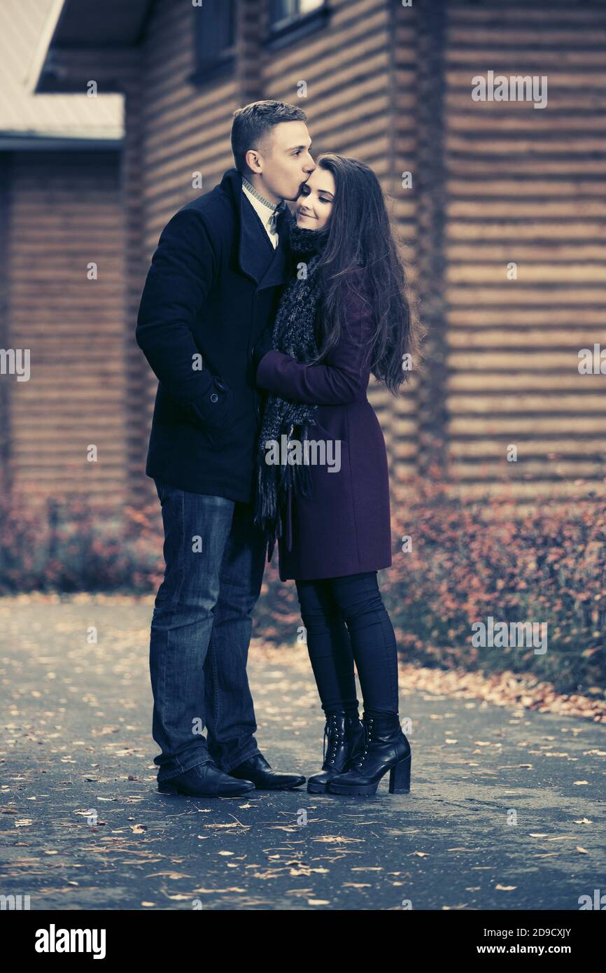 Felice giovane coppia di moda baciando su strada elegante uomo e. donna in cappotti classici Foto Stock