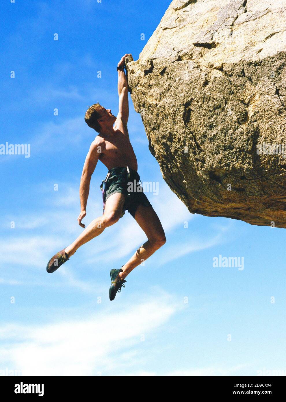 Un arrampicatore di roccia appeso su una roccia con una mano. Foto Stock
