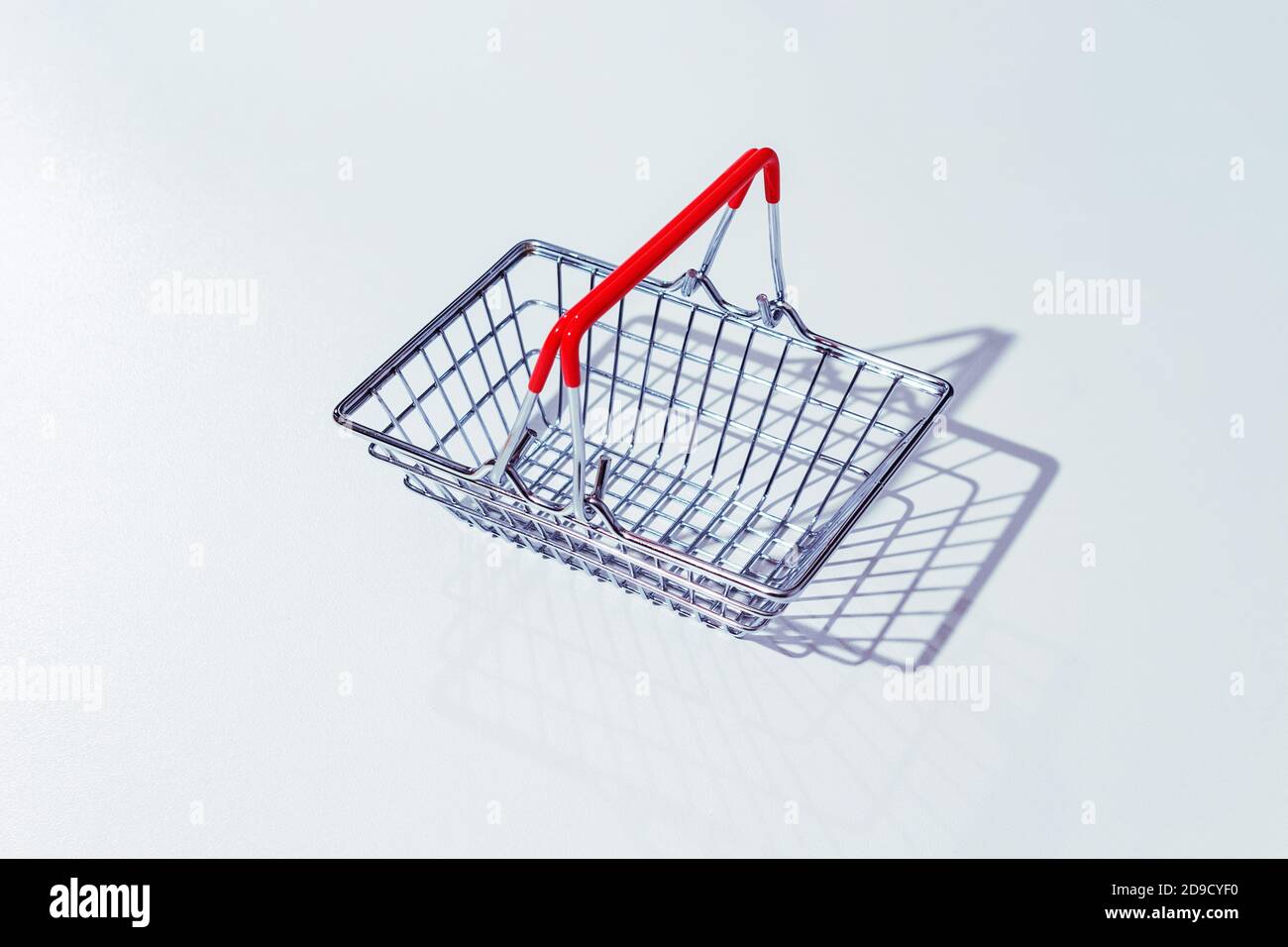 Cestino vuoto in metallo con maniglie rosse su sfondo grigio. Salario vivente. Ombre dure. Foto Stock