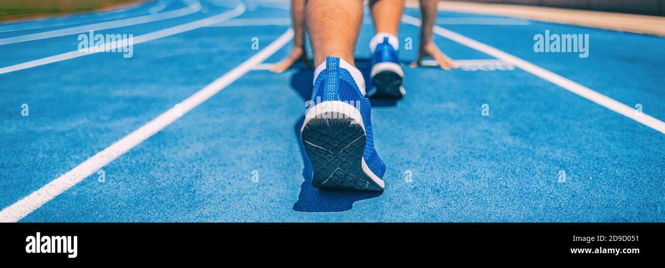 Sprinter fit uomo in attesa di inizio gara su piste da corsa allo stadio all'aperto. Atleta di atleta sportivo e fitness sulla pista blu di partenza con Foto Stock