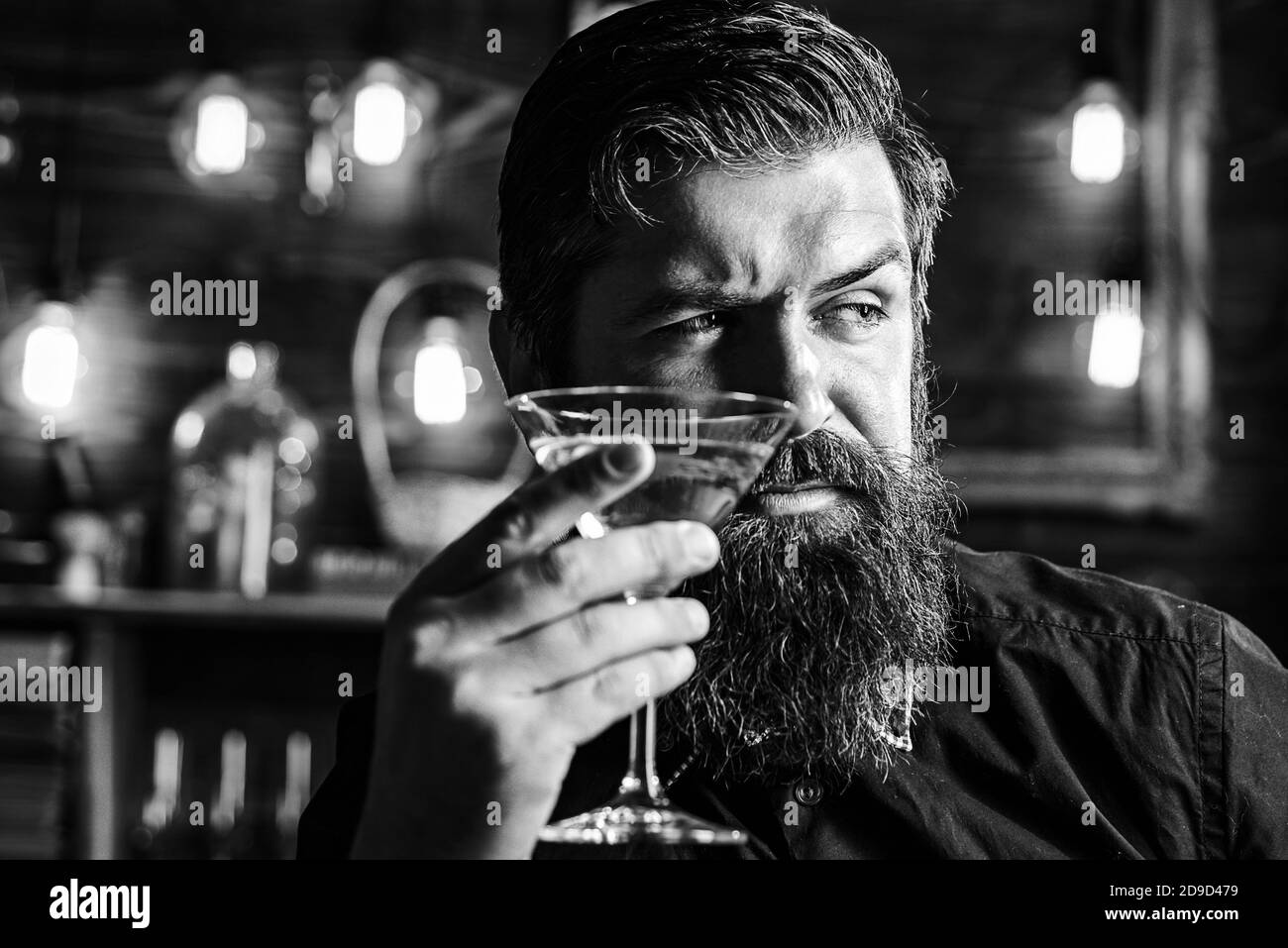 Barman hipster con martini o liquore. Uomo bearded che indossa il vestito e beve l'alcool. Concetto di festa per drink e celebrazioni. Degustazione e degustazione. Foto Stock