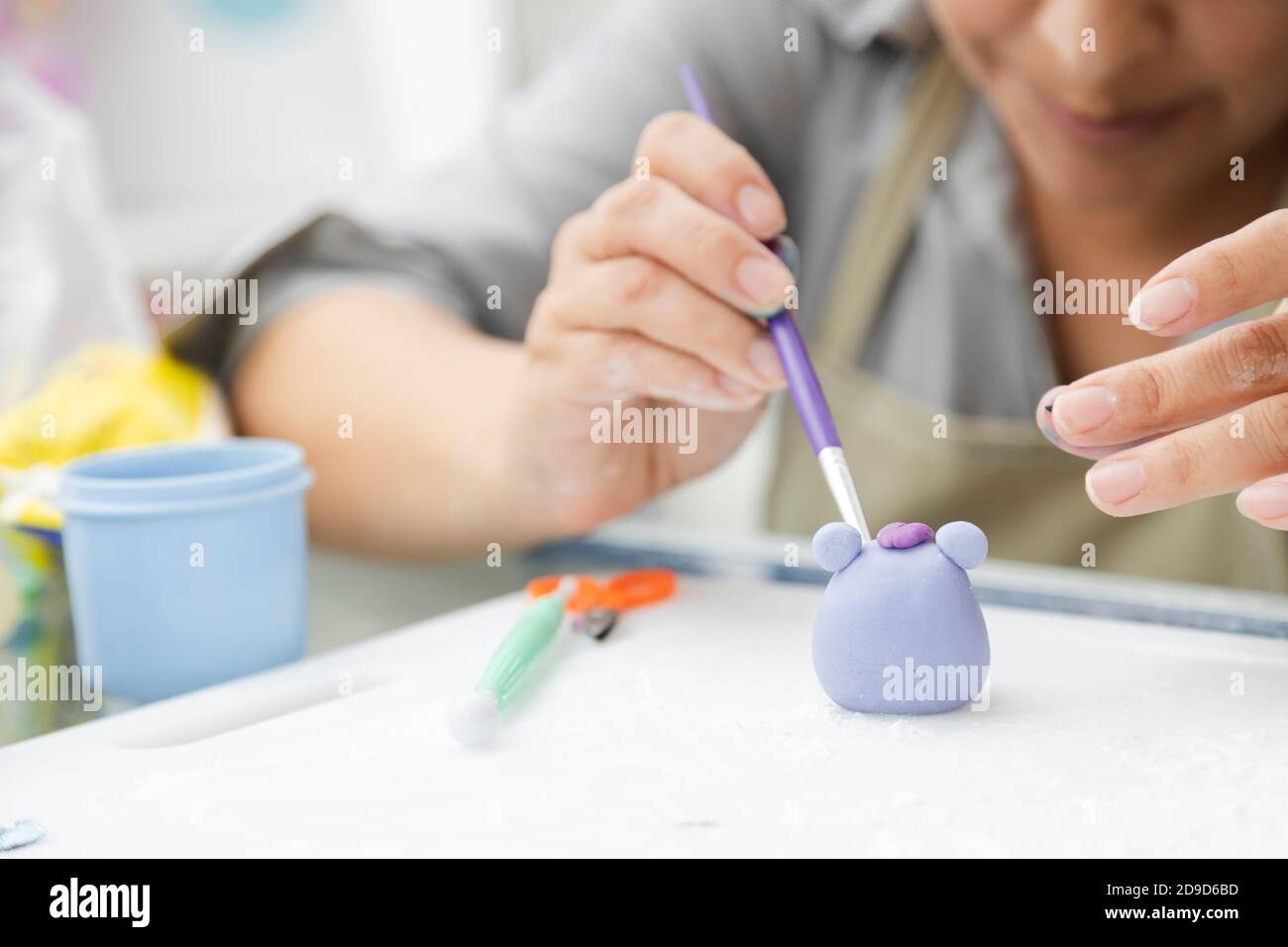 Primo piano delle mani della donna che lavorano con fondente per decorare una torta - donna pittura argilla con pennello e coloranti - donna craftswoman - creta stampaggio a. Foto Stock