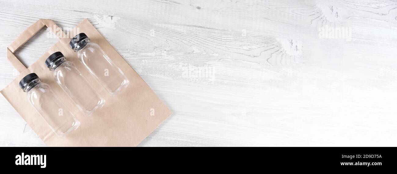 striscione. mockup, creatore di scene. sacchetto di carta, tre bottiglie di plastica. Confezionamento alimentare ecologico e sacchetti eco-compatibili in cotone su sfondo grigio con spazio per la copia Foto Stock