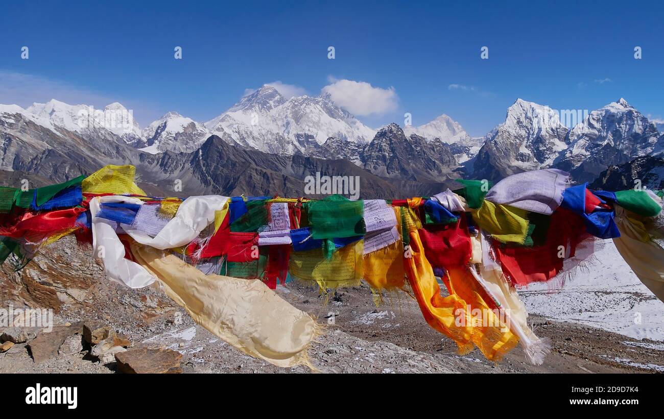 Colorate bandiere buddiste di preghiera che volano nel vento sulla cima del passo Renjo la (5,430 m), Himalaya, Nepal con spettacolare panorama montano. Foto Stock