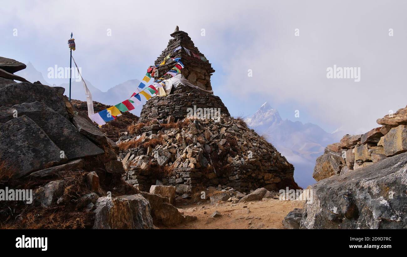 Monumento in pietra buddista con bandiere di preghiera colorate attaccate oltre al sentiero escursionistico vicino a Phortse, Sagarmatha National Park, Himalaya, Nepal. Foto Stock