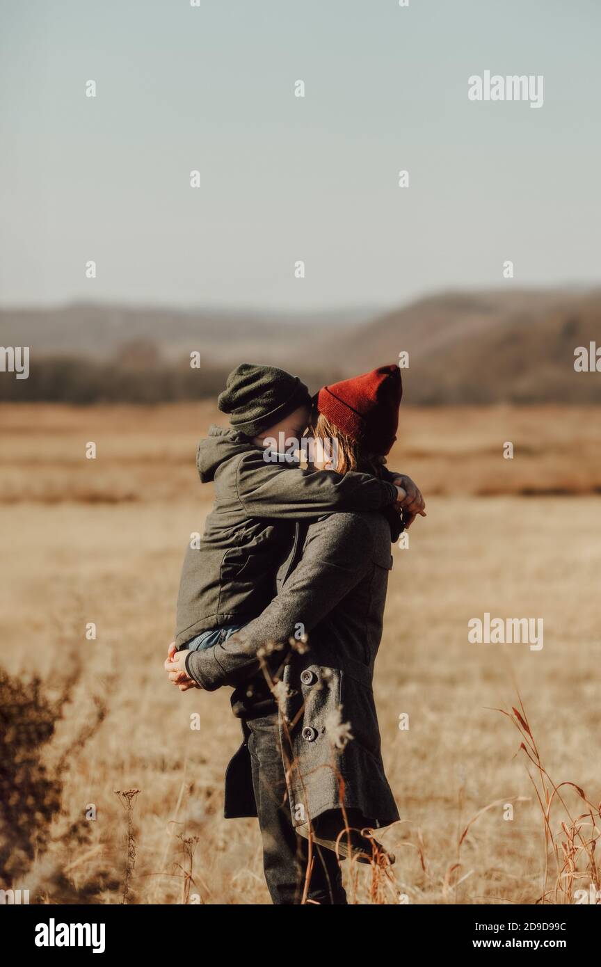 madre e figlio si abbracciano e toccano i loro nasi, con calore e stile vestito genitore e bambino sullo sfondo del campo d'autunno. Tessera vacanze giorno della mamma Foto Stock