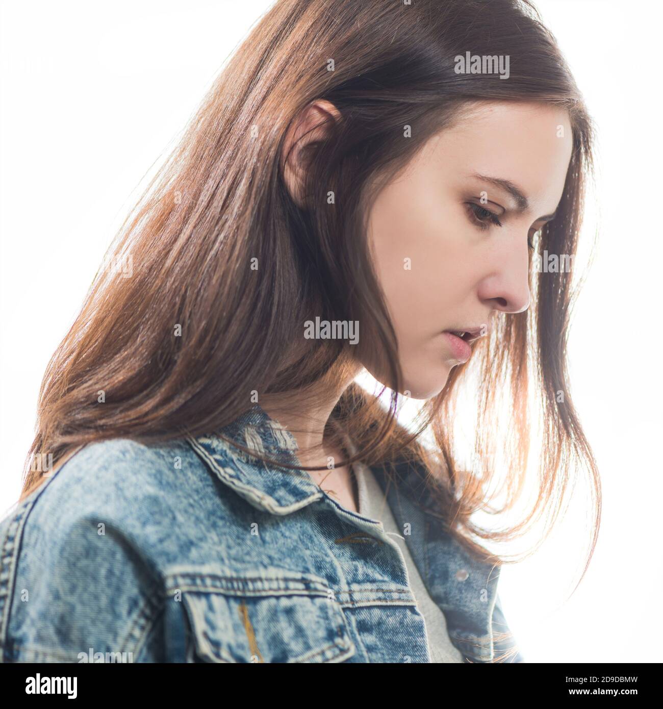 giovane shy brunet donna ritratto in jeans giacca isolato su sfondo bianco Foto Stock