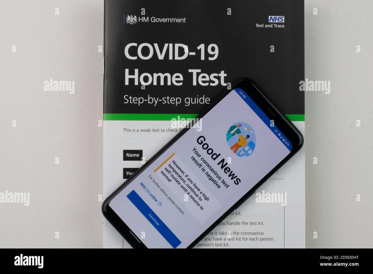 Risultato negativo del test del coronavirus sul telefono cellulare poggiato sul libretto di istruzioni per il kit di test COVID-19 home. Foto Stock