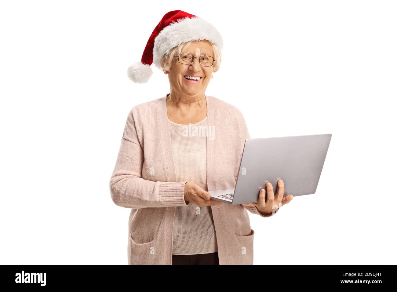 Donna anziana felice che tiene un computer portatile e che indossa un cappello di babbo natale isolato su sfondo bianco Foto Stock