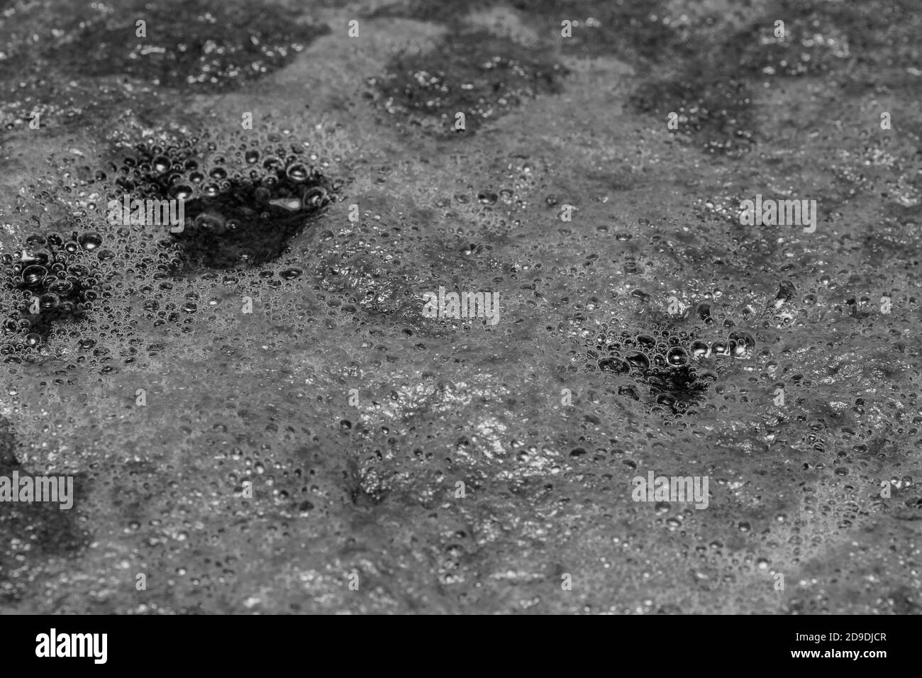 Formazione di bolle d'aria in bianco e nero sulla superficie dell'acqua, messa a fuoco selettiva, vista dall'alto, spazio di copia Foto Stock