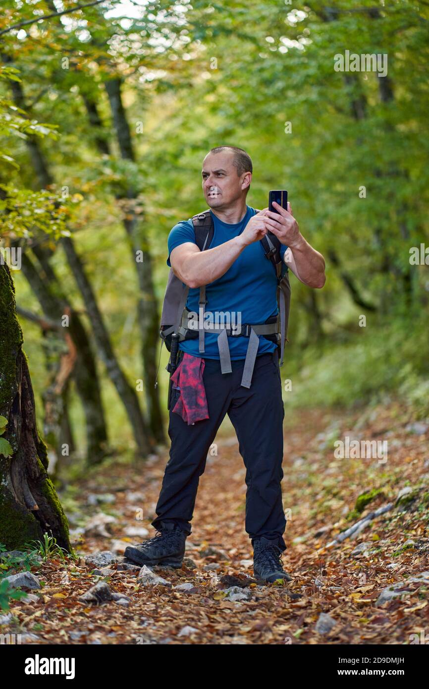 L'escursionista cerca di ottenere il segnale gps al suo telefono a. continua a fare escursioni Foto Stock
