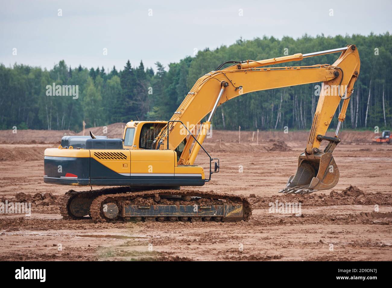 Il moderno escavatore cingolato attraversa un campo fangoso Foto Stock