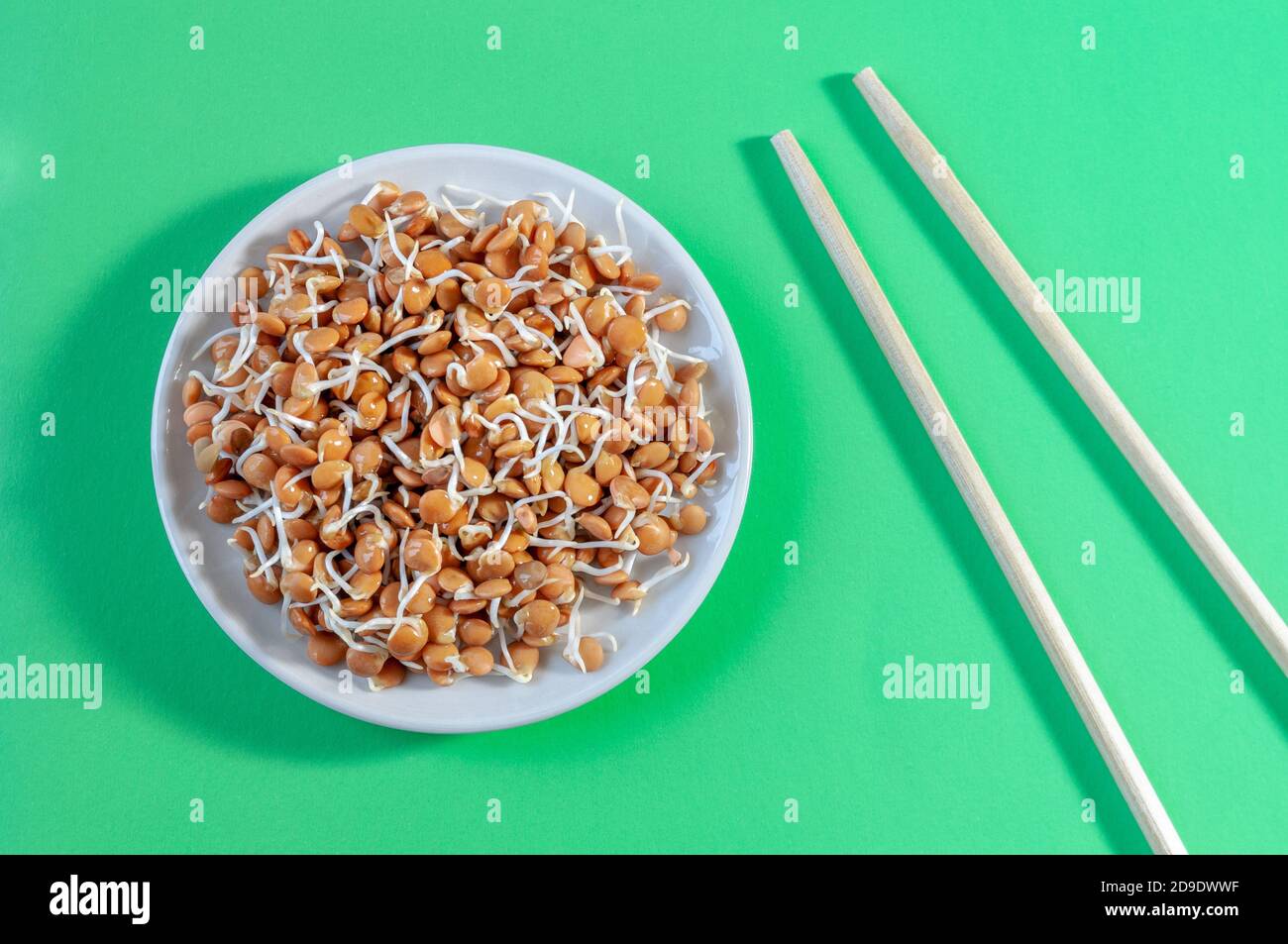 piatto con germogli di lenticchie e bastoncini su sfondo verde Foto Stock