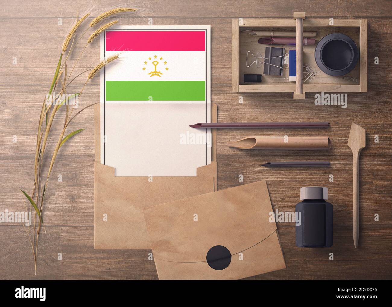 Invito al Tagikistan, concetto di lettera di celebrazione. Bandiera con carta artigianale e busta. Tema retrò con dividere, inchiostro, oggetti penna di legno. Foto Stock