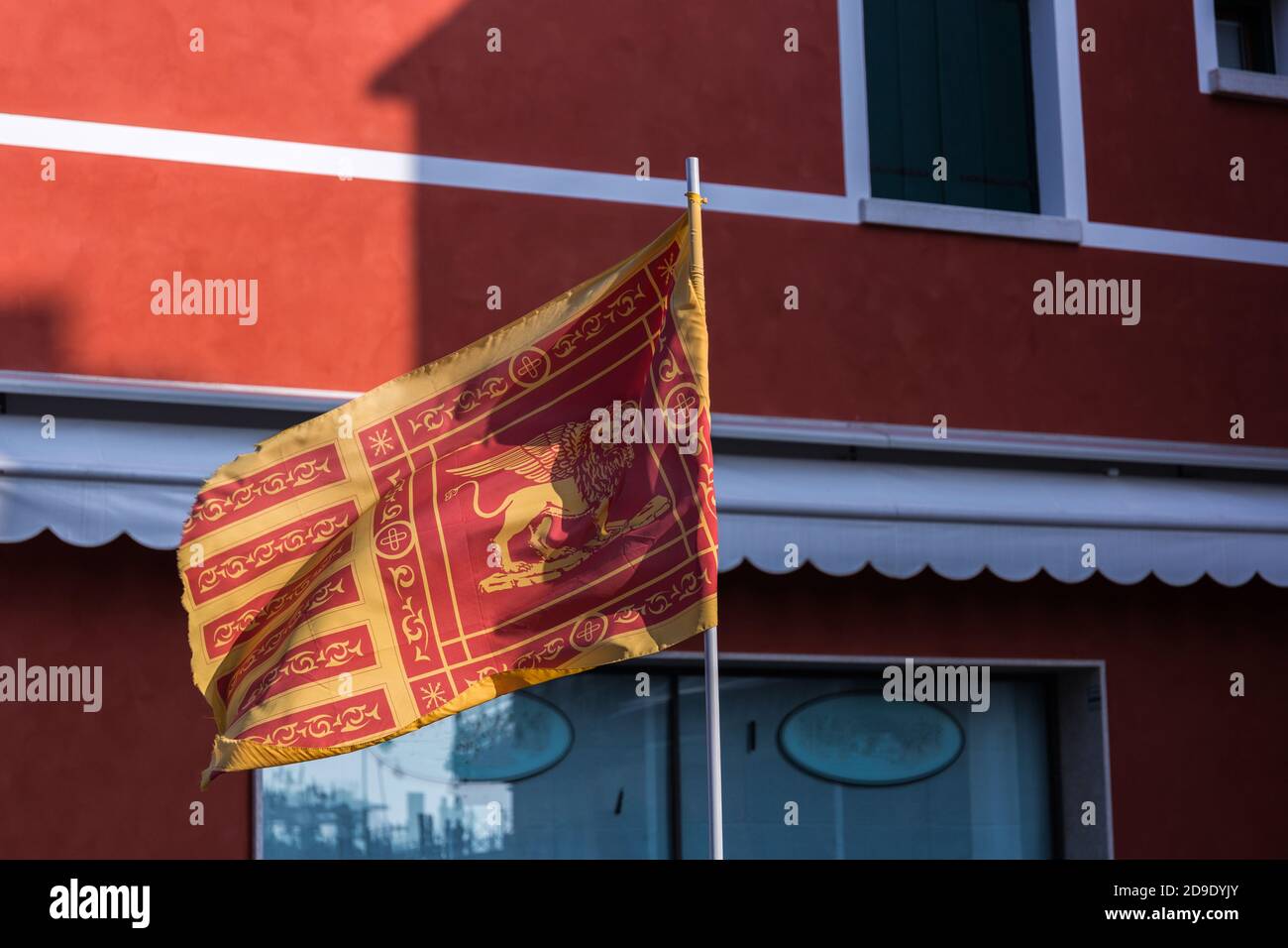 Bandiera della Repubblica di Venezia con un edificio rosso sullo sfondo Foto Stock