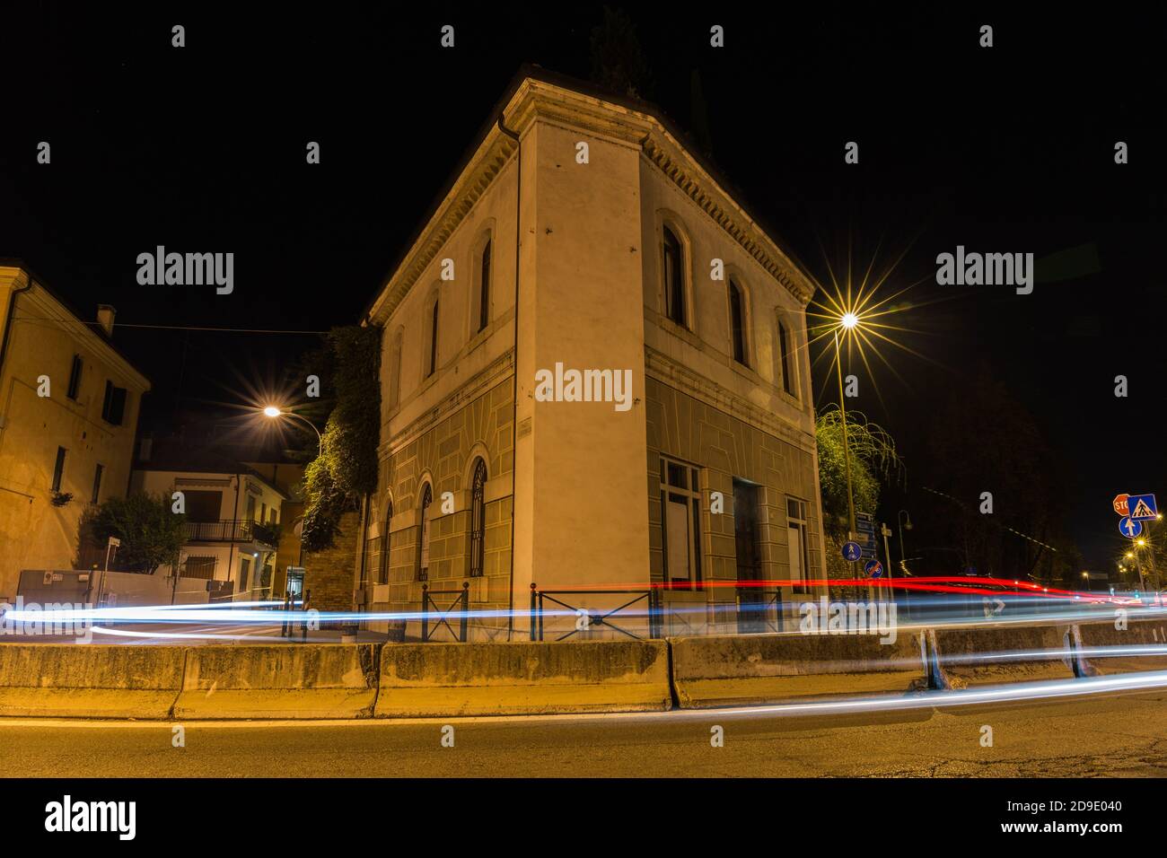 Edificio di forma triangolare con strada davanti ad esso e Luci auto di notte Treviso Italia Foto Stock