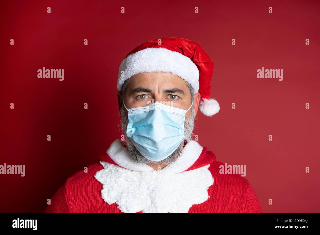 Ritratto dell'uomo con maschera medica e cappello Babbo Natale. Festa di Natale durante la pandemia del coronavirus Foto Stock