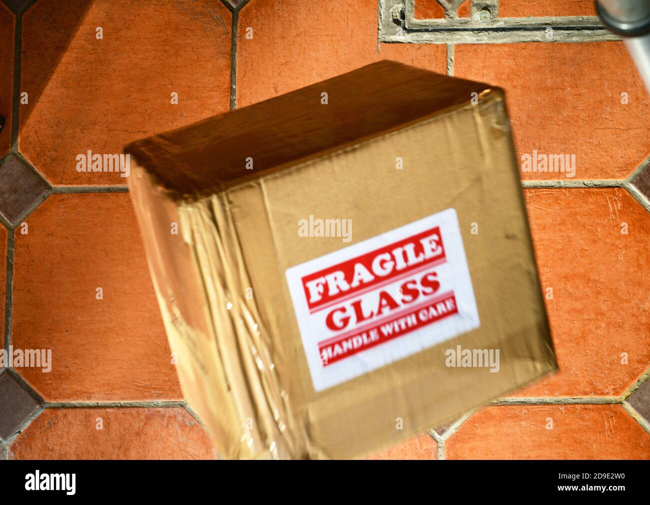 il pacco fragile viene fatto cadere sul pavimento delle piastrelle Foto Stock