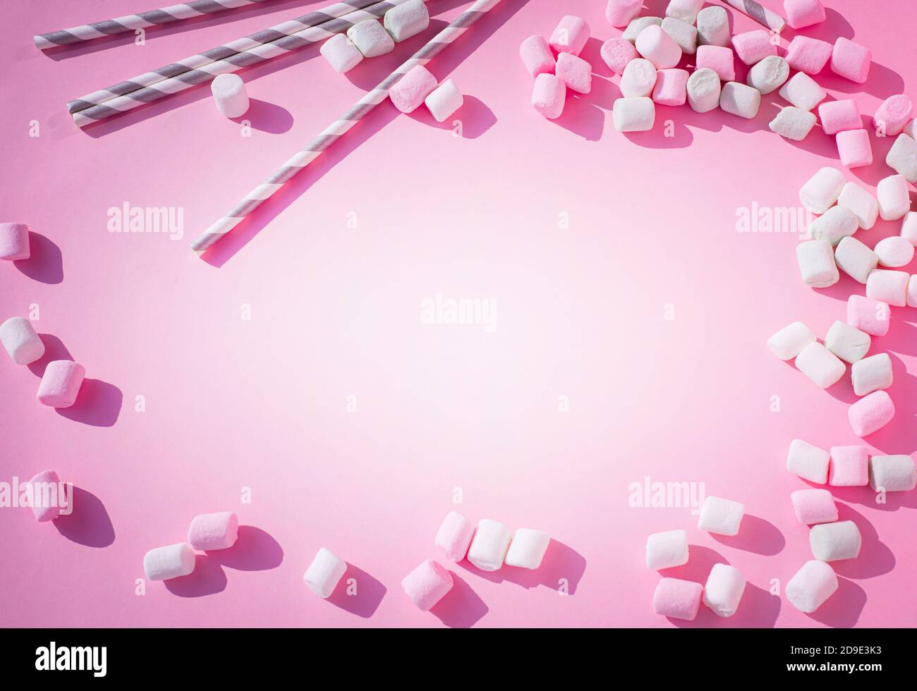 Sfondo rosa con una cornice di marshmallow rosa e cannucce per bevande. Foto Stock