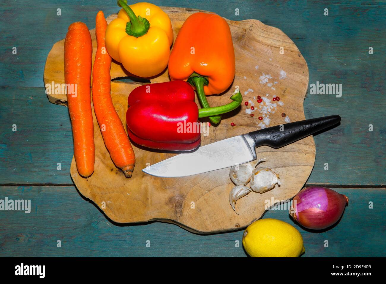 Verdure fresche crude. Peperoni colorati con carote, limone e cipolla su tagliere di legno. Immagine stock. Foto Stock