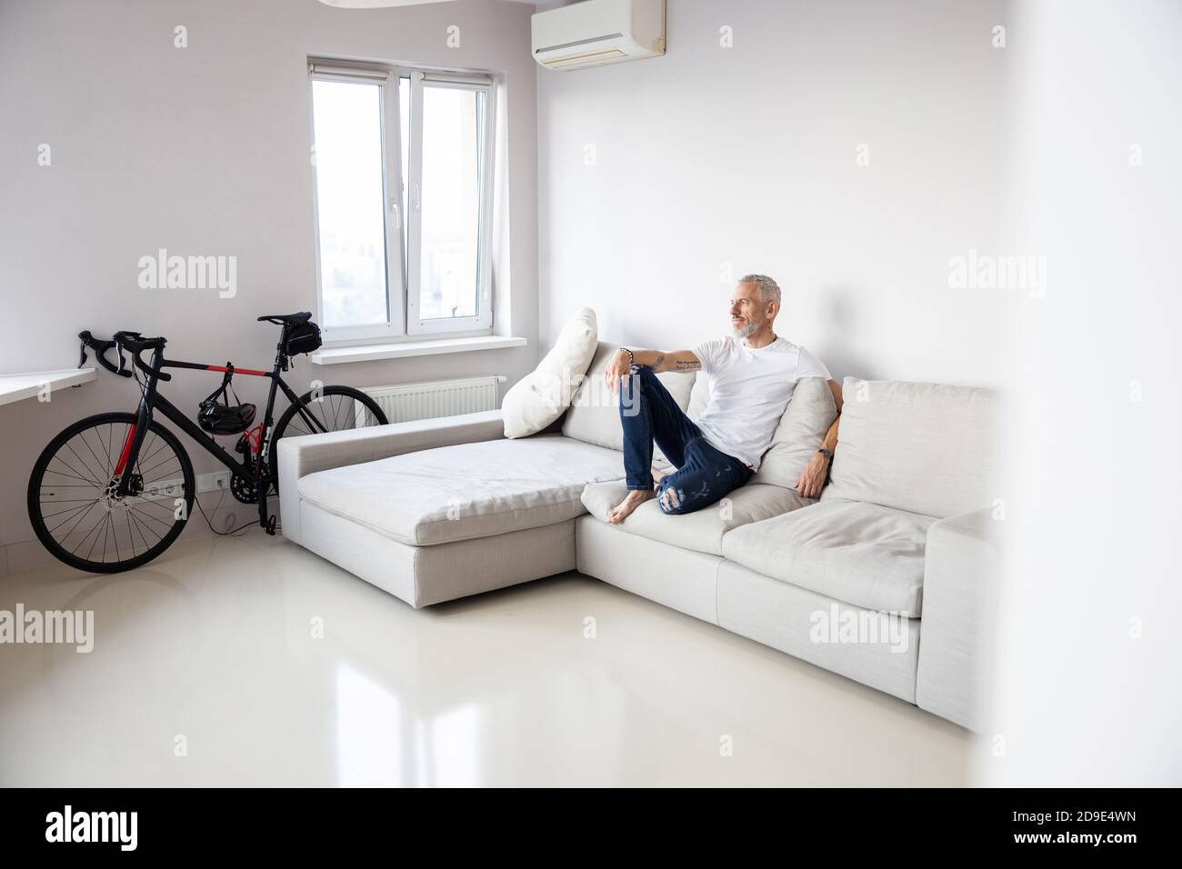 L'uomo è seduto su un divano bianco Foto Stock