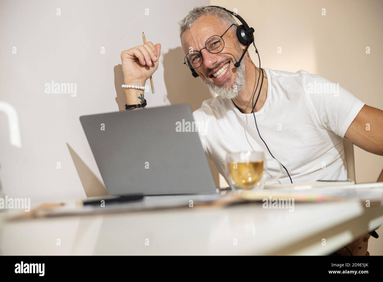 L'uomo anziano con una matita e una cuffia che amano il suo lavoro Foto Stock