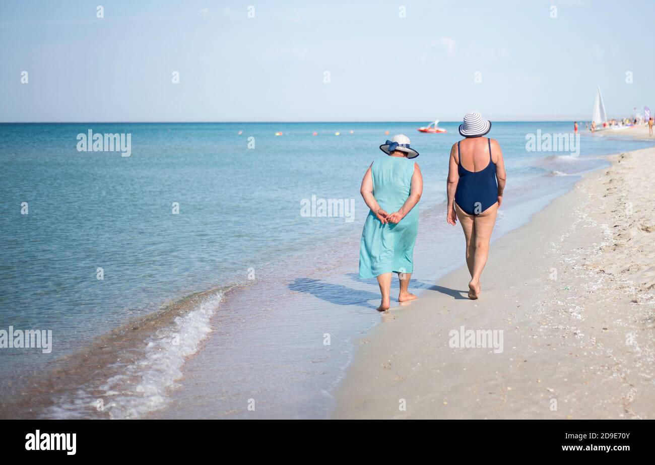 Due Signore anziane camminano lungo la riva. Felice vecchiaia. Viaggio in pensione. Spazio di copia per il testo. Foto Stock